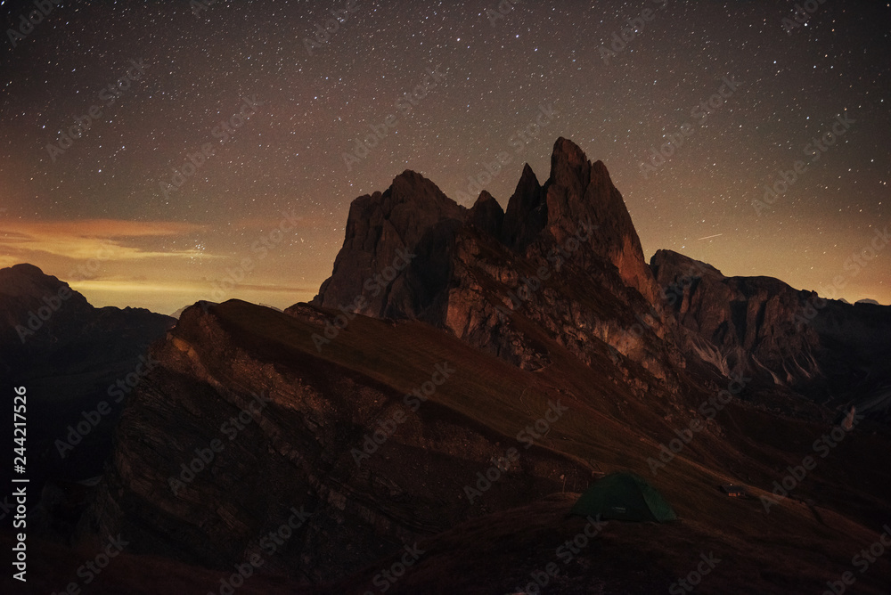 Night photo of Seceda dolomites mountains. Tourists resting in the green tent