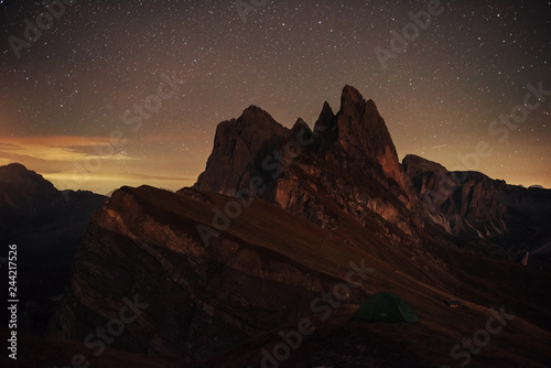 Night photo of Seceda dolomites mountains. Tourists resting in the green tent