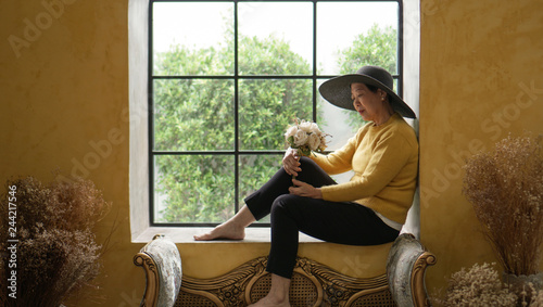 Asian senior woman sit in Europe style window sunlight, luxury travel