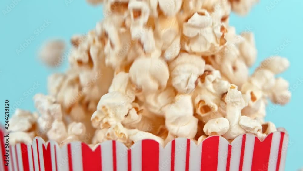 Falling popcorn in super slow motion on blue background.