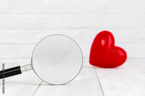 Magifying glass with red heart shaped on white background, find love concept