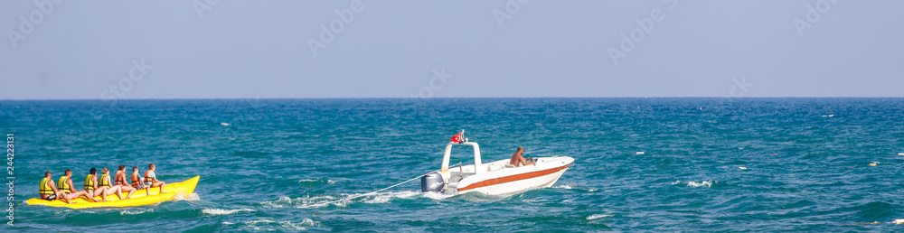 Naklejka premium group of young people riding banana boat