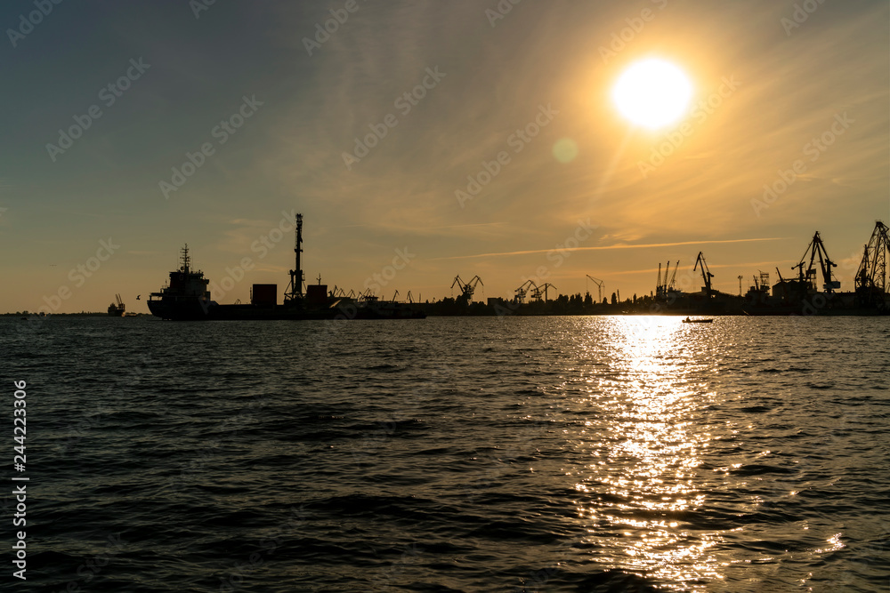 Silhouettes of seaport cranes at sunset. Evening panorama of the cargo port, Ukraine, Kherson