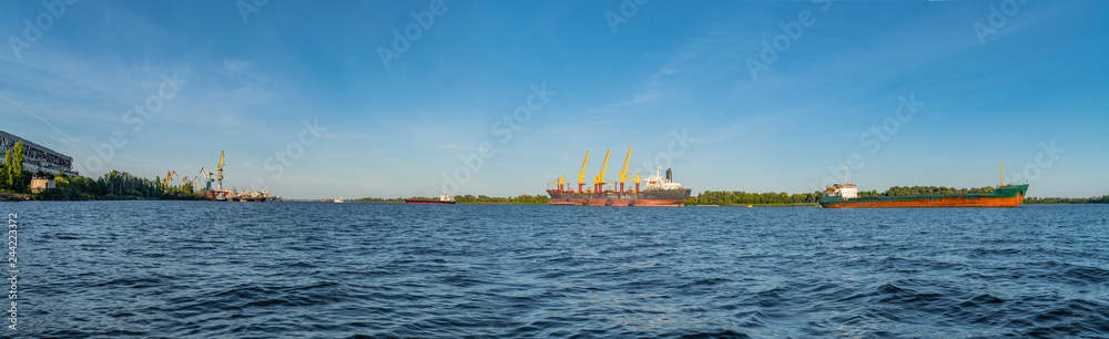 Seaport city and navigable river with ships. Panorama view