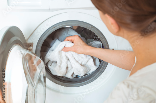 A woman loads dirty clothes for a washing machine. 