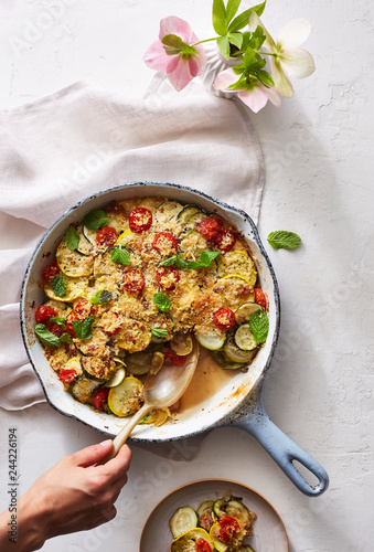 Zucchini and Mint Gratin in pan with hand spooning out photo