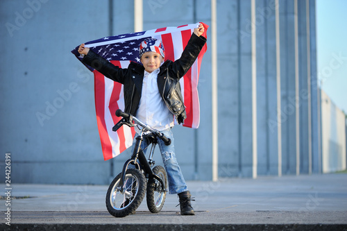 Happy handsome boy  smiling and waving American flag outside, wearing  Jackster Bandana. Child celebrating 4th july - Independence Day of USA. photo