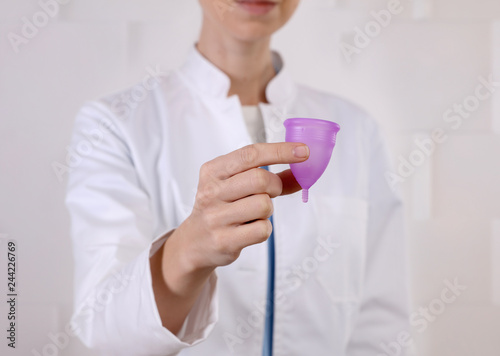 Doctor gynecologist holding menstrual cup. Female period, intimate hygiene concept