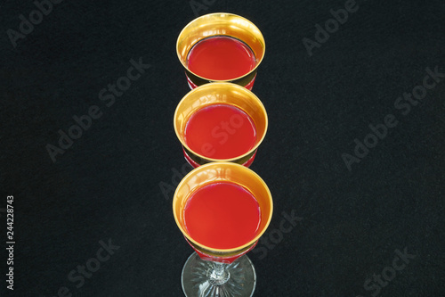 Golden glasses filled with a red liquid in black background photo