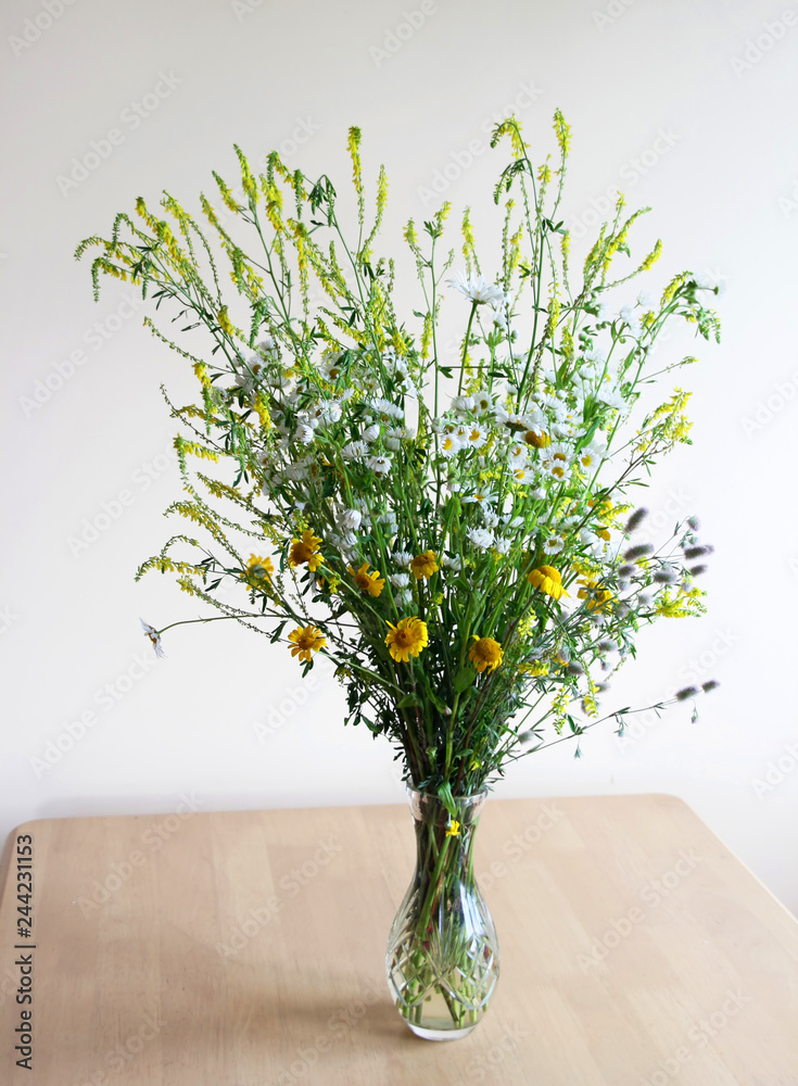 Beautiful wild flowers in a glass vase on the table.