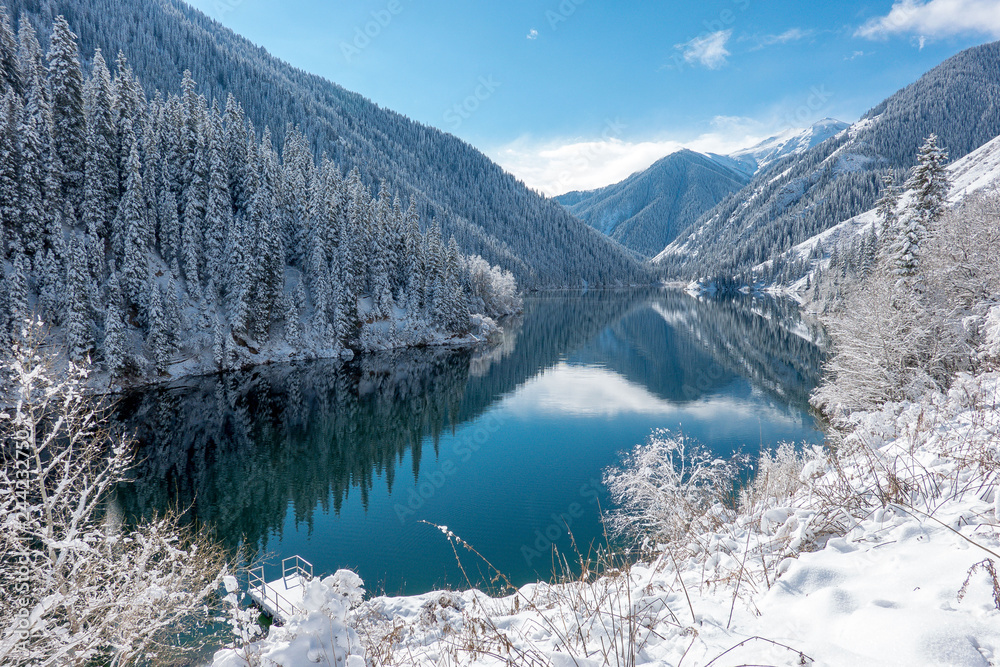 Mountains and frozen forest are reflected in a blue lake