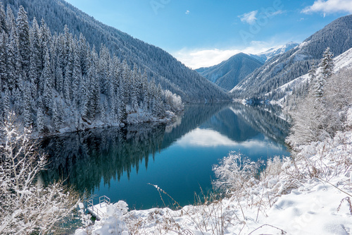 Mountains and frozen forest are reflected in a blue lake