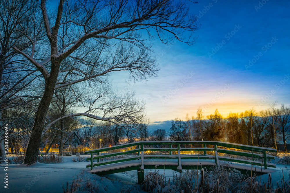 Obraz premium Sun sets over Park in Elk covered with snow.