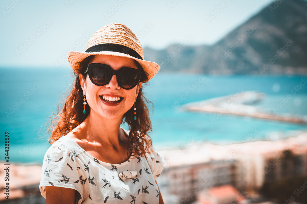 Happy tourist woman with straw sunhat looking to the mediterranean sea and enjoying the blue and scenic seascape in Altea, Alicante, Spain. Teal and orange look. Happy tourist woman with straw sunhat looking to the mediterranean sea and enjoying the blue and scenic seascape in Altea, Alicante, Spain. Teal and orange look.