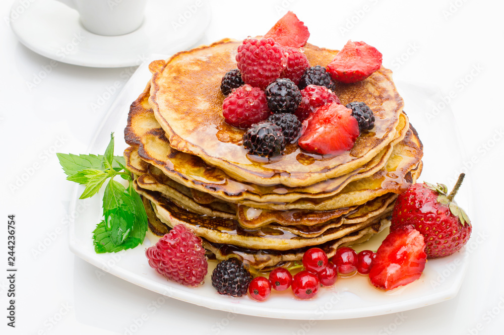 Delicious pancakes with berries and maple syrup on a white background