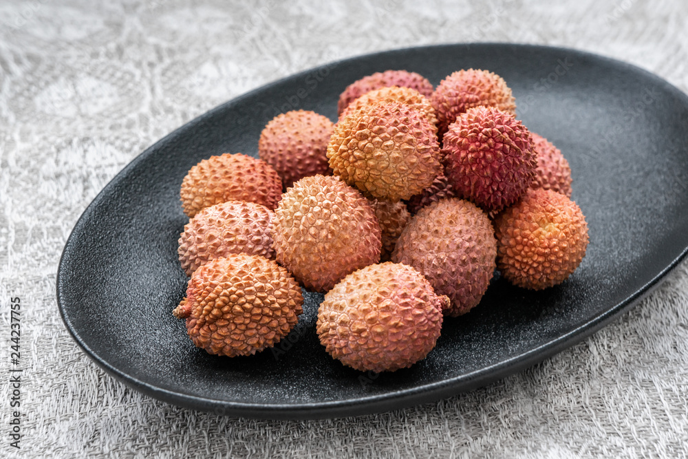 Fresh organic lychee fruit in a bowl on a black dish. Healthy vegan food concept. Close-up