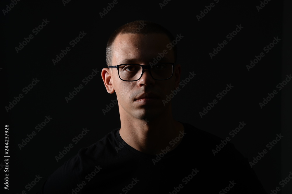 a man in a black jacket shows emotions in the Studio on a black background