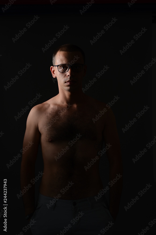 a man shows his torso and posing in the Studio on a black background a man shows his torso and posing in the Studio on a black background