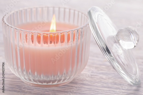 Pink candle burning in a glass beaker on an old white wooden table.