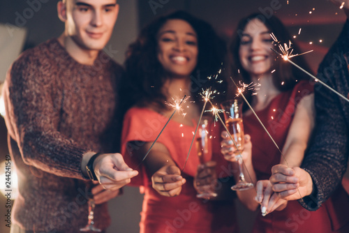 Smiling and feel happy. Multiracial friends celebrate new year and holding bengal lights and glasses with drink