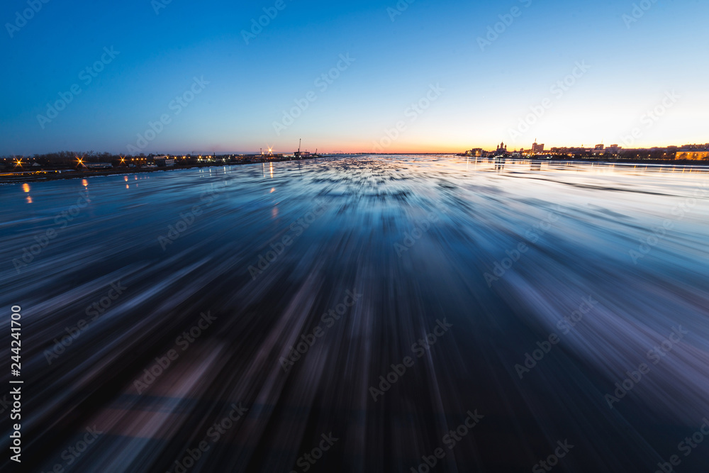 Ice drift in Northern Dvina river in Arkhangelsk, Russia. Beautiful ice motion evening panoramic landscape.