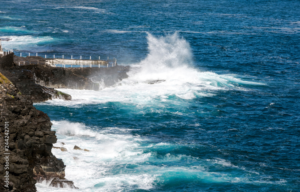 Waves breaking along the rocks in Tenerife, in the Canary Islands on a sunny day.