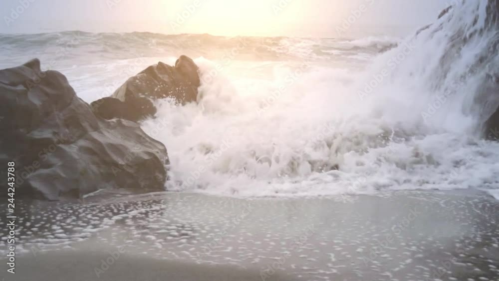 Move Left Behind Rock at Waves Crashing on Shore. slow motion move left from behind a rock to revealwater crashing into the rocks at shoreline