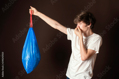 attractive male hold smelly garbage bag isolated. take out trash concept s photo