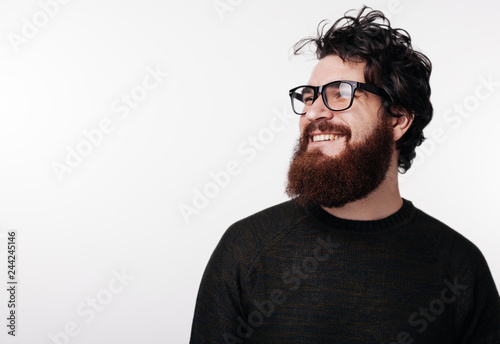 Attractive bearded man with stylish hair and beard smiling and looking away
