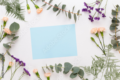 Flowers composition. Paper blank, carnation flowers, eucalyptus branches on pastel  background. Flat lay, top view, copy spaceFlat lay stiil life. photo