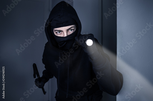 Einbrecher mit Taschenlampe und Brecheisen in Wohnung 