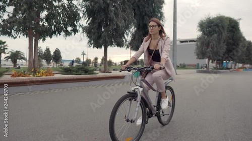 Young townswoman is riding bike in city in summer day, view on her face