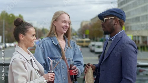 Tilt-up shot of young people standing on the street talking and holding bottles with drinks