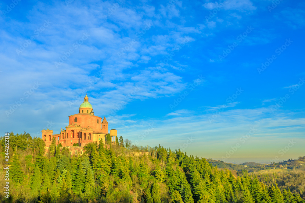 Scenic landscape of Sanctuary of Blessed Virgin of San Luca on Colle della Guardia in Bologna. Sunset light, blue sky. Historical church and pilgrimage destination in Emilia-Romagna, Italy. Copy space