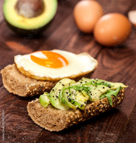 Two different bruschettas with avocado, rucola sesame, seeds, egg on wooden table