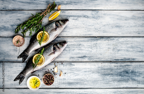 Fresh fish sea bass. Sea bass raw fish with ingredients spices and herbs on wooden background . Top view with copy space. 
