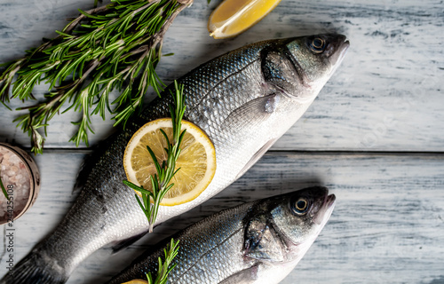 Fresh fish sea bass. Sea bass raw fish with ingredients spices and herbs on wooden background