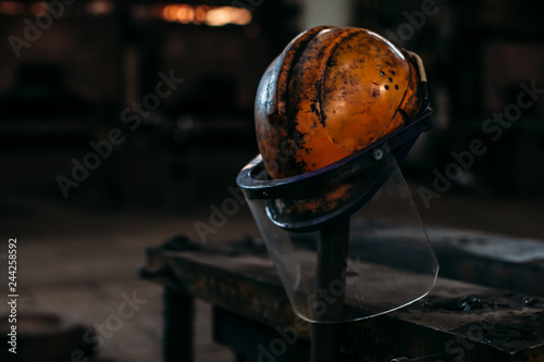 Old orange construction helmet on a factory, put on a stick