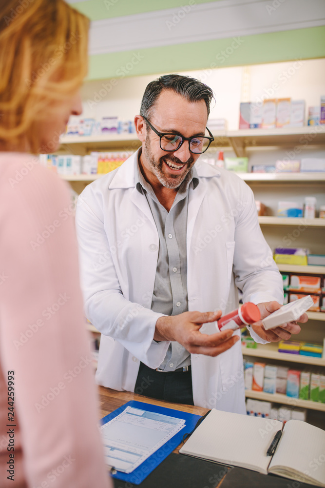 Chemist suggesting medical drug to buyer at pharmacy Chemist suggesting medical drug to buyer at pharmacy