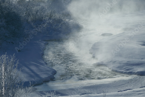 Rising mist from a warm river surrounded by snow covered fields on a cold morning, Stowe, Vermont, USA