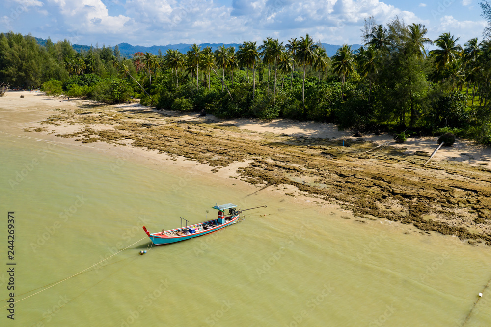 Aerial view of a colorful traditional Thai Longtail boat moored off a small sandy beach in Khao Lak