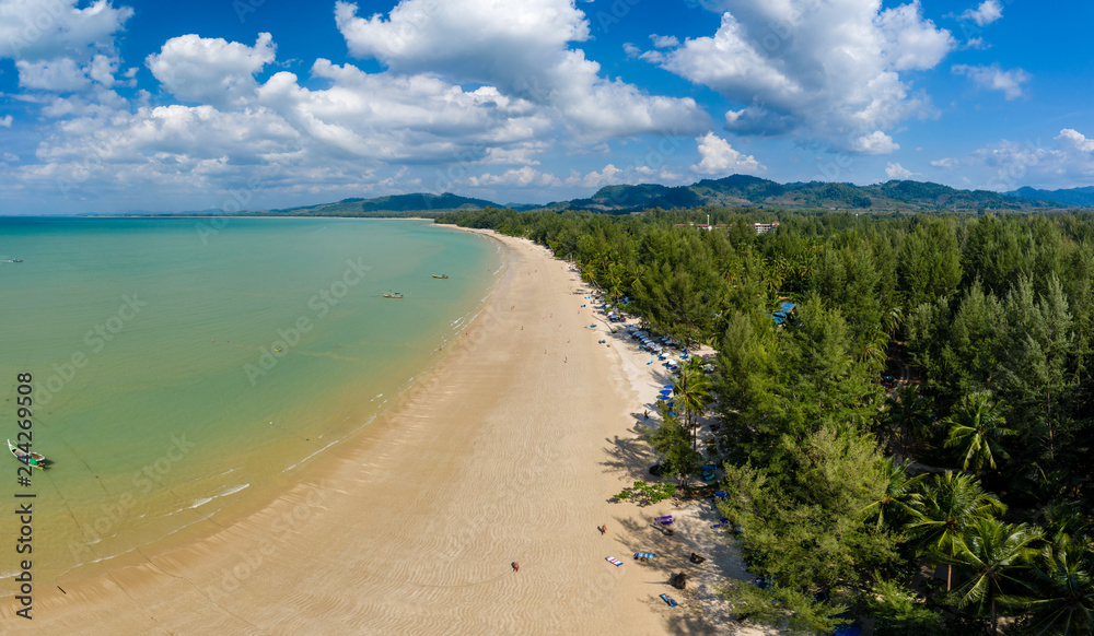 Aerial panoramic view of a beautiful tropical beach with traditional boats surrounded by lush greenery (Khao Lak, Thailand)