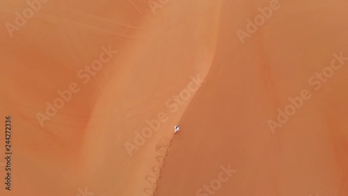 emirati man walking in massive sand dunes of Liwa desert, part of Empty Quarter desert