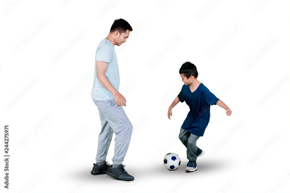Little boy playing football with his father on studio