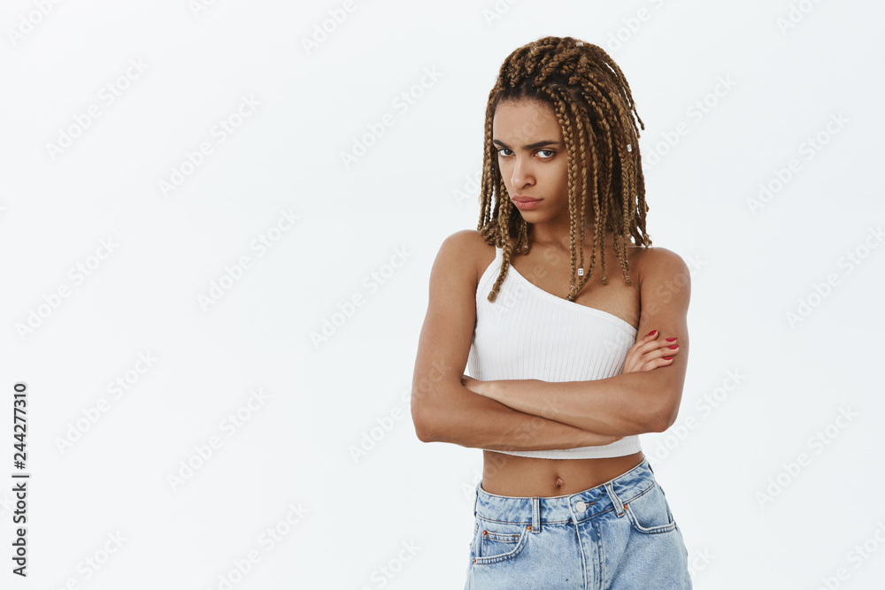 She do not trust us. Intense displeased and gloomy serious-looking smart dark-skinned woman with dreads frowning looking from under forehead crossing arms on chest from offence or disbelief She do not trust us. Intense displeased and gloomy serious-looking smart dark-skinned woman with dreads frowning looking from under forehead crossing arms on chest from offence or disbelief