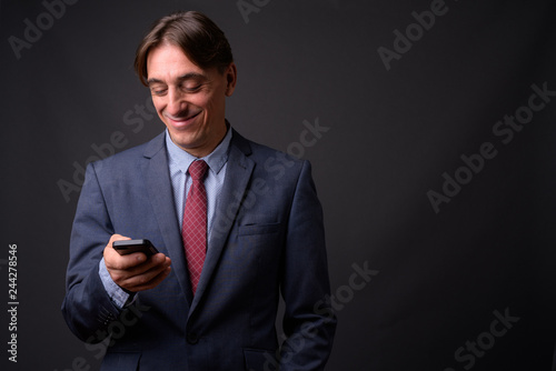 Mature happy Italian businessman using mobile phone
