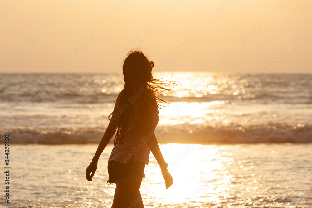 silhouette of a girl with long hair on the background of the ocean sunset