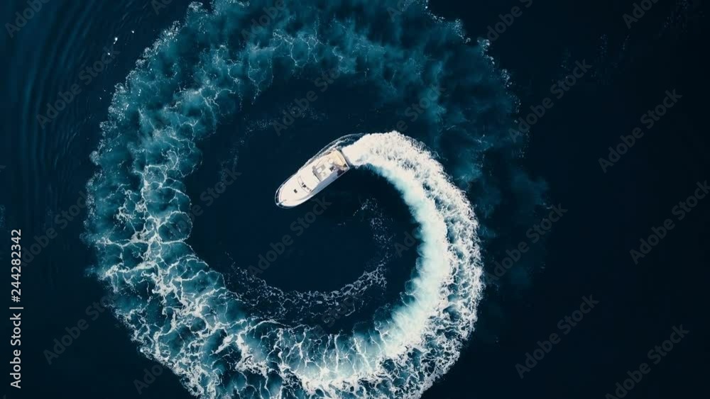 Aerial view of Circle of waves Motor boat on the azure sea of Montenegro against the backdrop of the mountains in summer