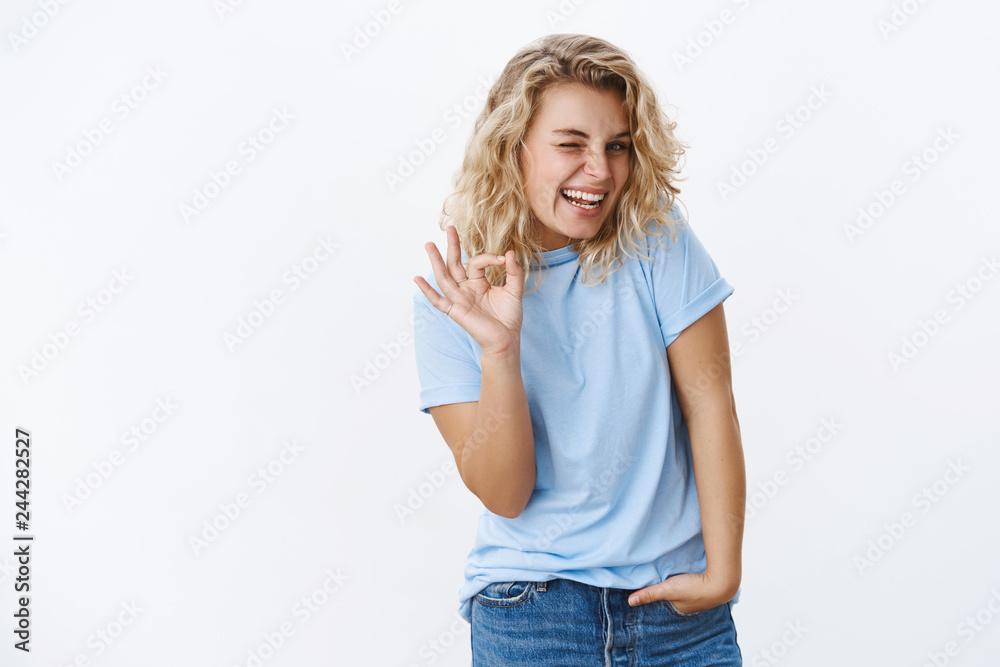 Girly girl giggling winking joyfully and flirty as showing okay gesture saying no problem saying ok and smiling pleased and excited as agree keep secret over white background Girly girl giggling winking joyfully and flirty as showing okay gesture saying no problem saying ok and smiling pleased and excited as agree keep secret over white background