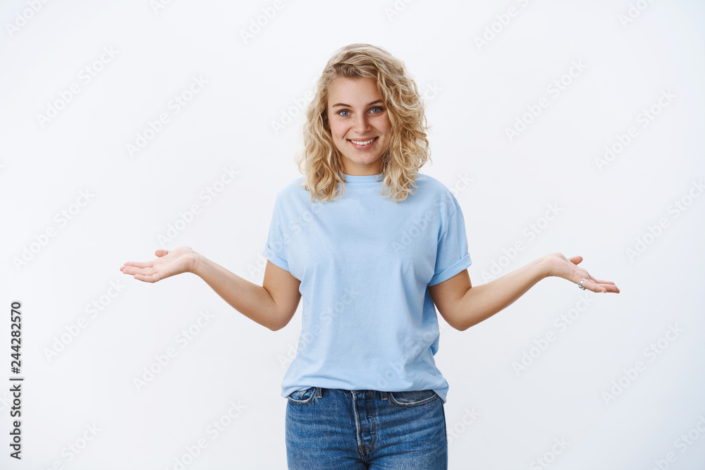You have two choices. Portrait of pleasant happy and relaxed charming blond female with blue eyes in t-shirt present product holding hands sideways as if making decision and smiling broadly You have two choices. Portrait of pleasant happy and relaxed charming blond female with blue eyes in t-shirt present product holding hands sideways as if making decision and smiling broadly